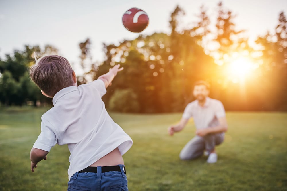 A child throwing a football to an adult at Heartland Ranch.